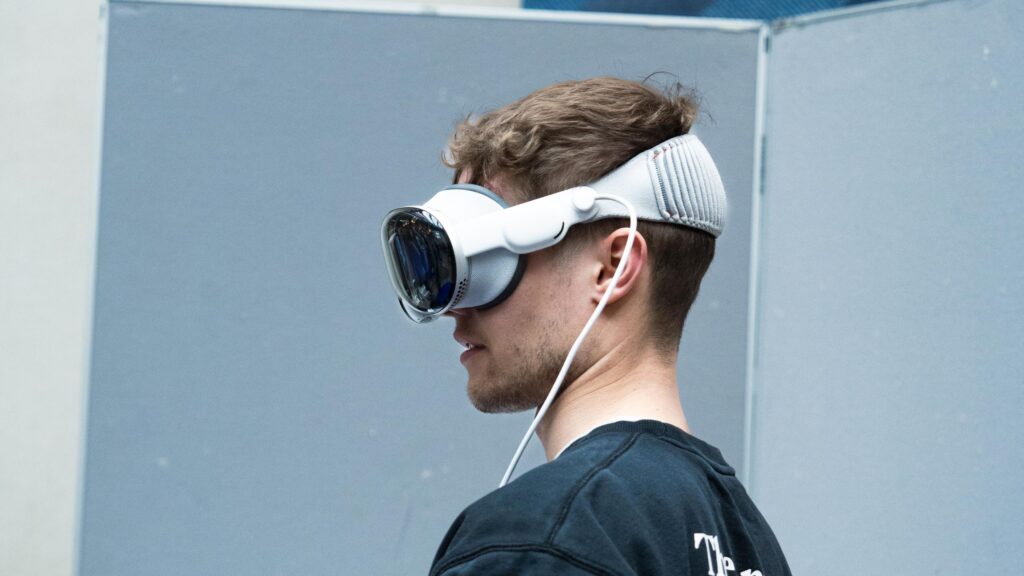 A photo of a man wearing an electronic virtual reality device called the Apple Vision Pro. A photo of one of many tech displays at Tech Day.